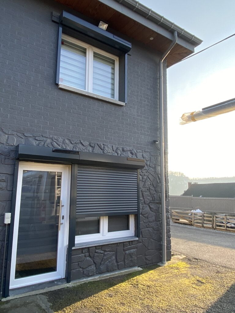 volets gris sur porte et fenêtres de façade en brique et pierre grise