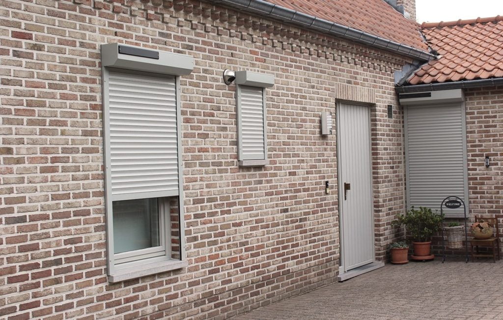 Façade en brique équipée de volets blancs aux fenêtres